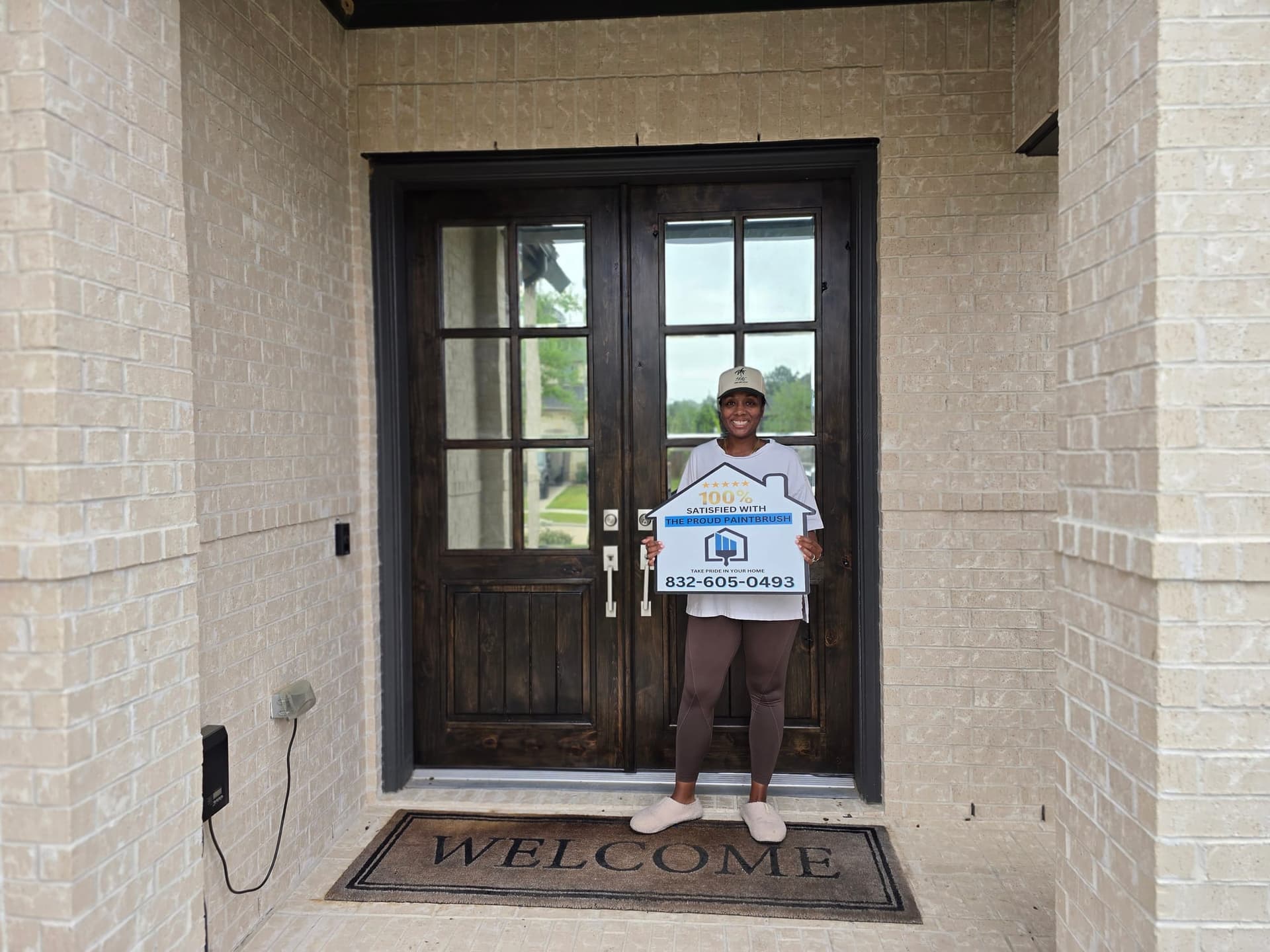 Exterior painting customer in Fulshear TX in front of freshly painted home and refinished door