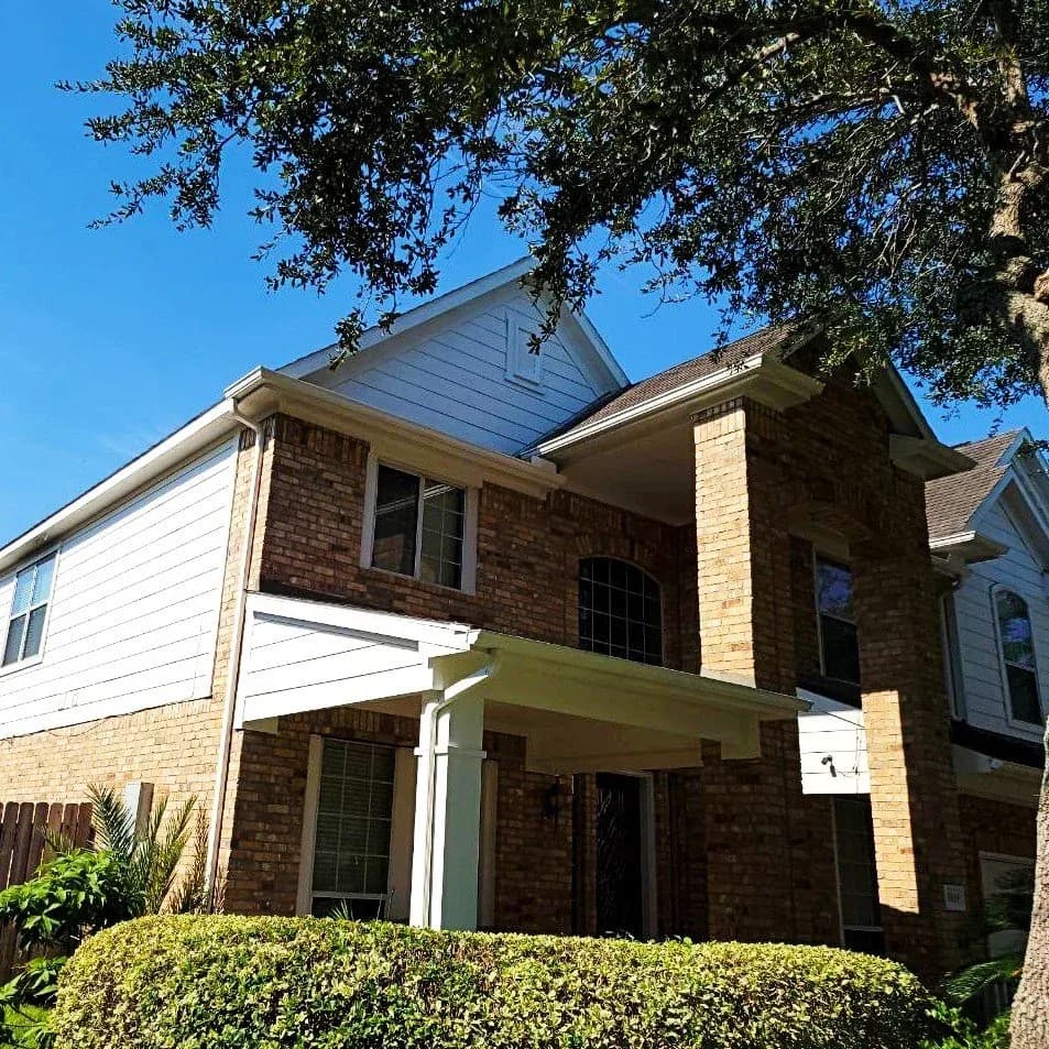 Brick two-story home exterior repainted in Fulshear, TX by The Proud Paintbrush