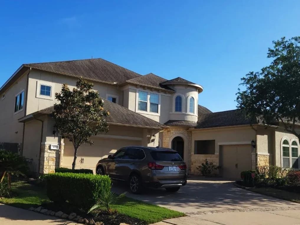 Large tan stucco home exterior repainted in Sugar Land, TX by The Proud Paintbrush