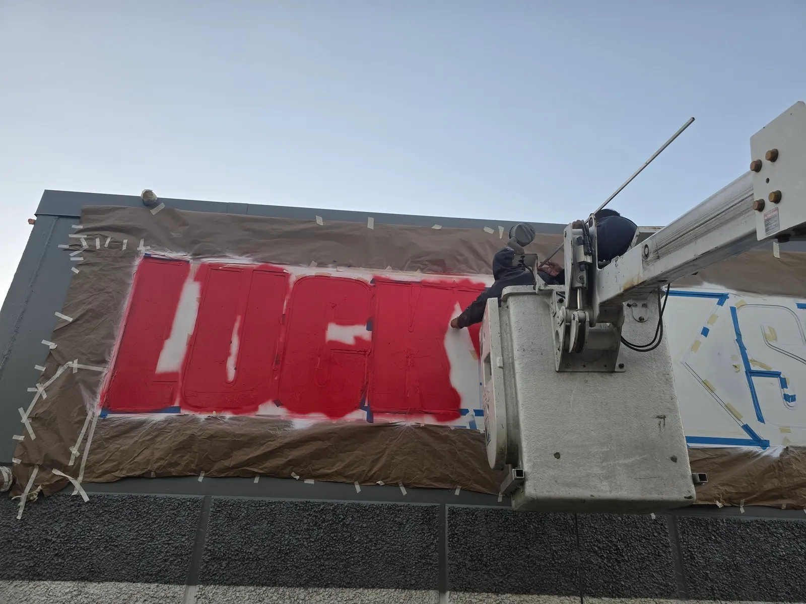 Painter spraying a commercial building sign in West Houston, TX by The Proud Paintbrush