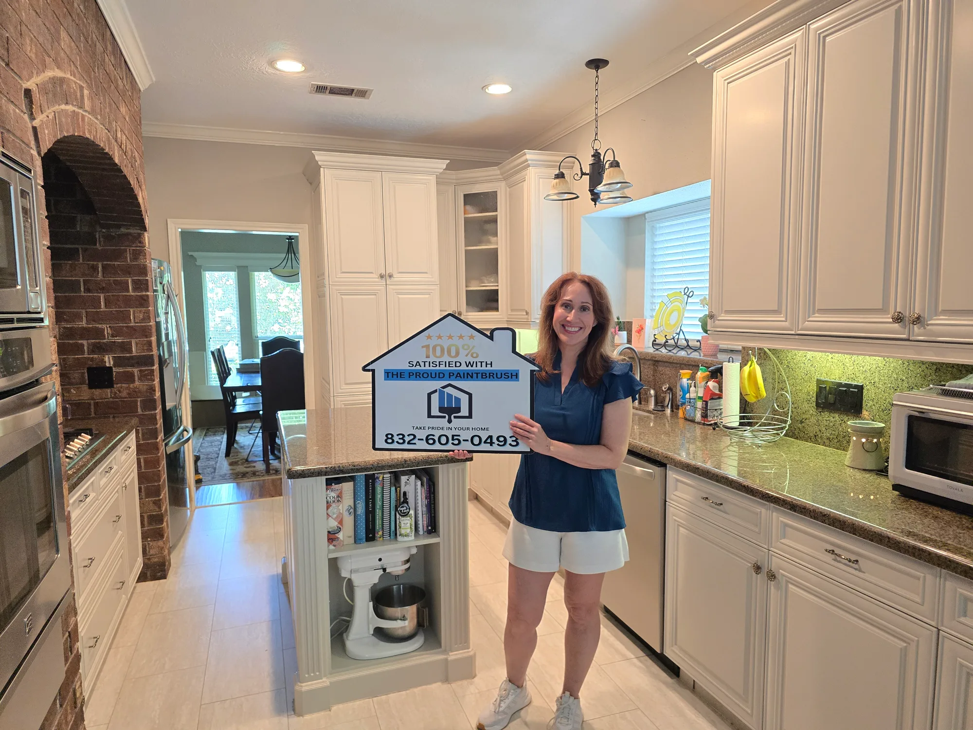 Happy homeowner with a 100% satisfied sign after kitchen cabinet refinishing in Memorial Parkway, Katy TX