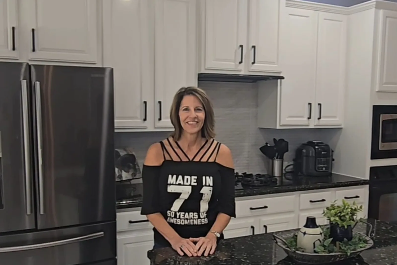 Amy, a Cinco Ranch homeowner, in her refinished white kitchen after cabinet painting in Katy, TX