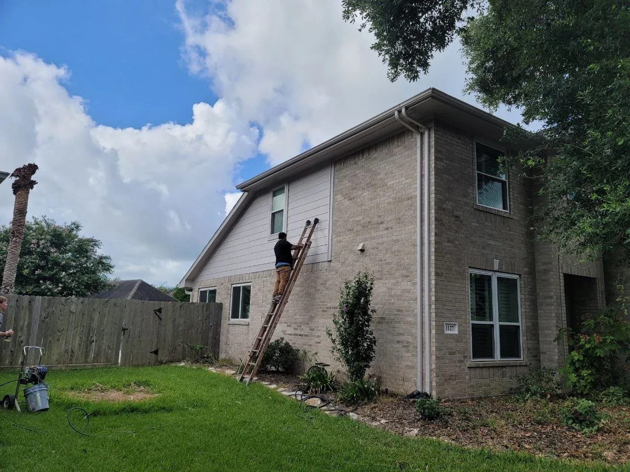 Exterior repaint in progress on a brick two-story home in Sugar Land, TX by The Proud Paintbrush