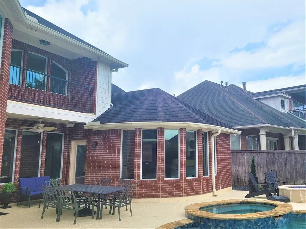 Freshly painted two-story brick home with crisp white trim and a patio in Sugar Land by The Proud Paintbrush