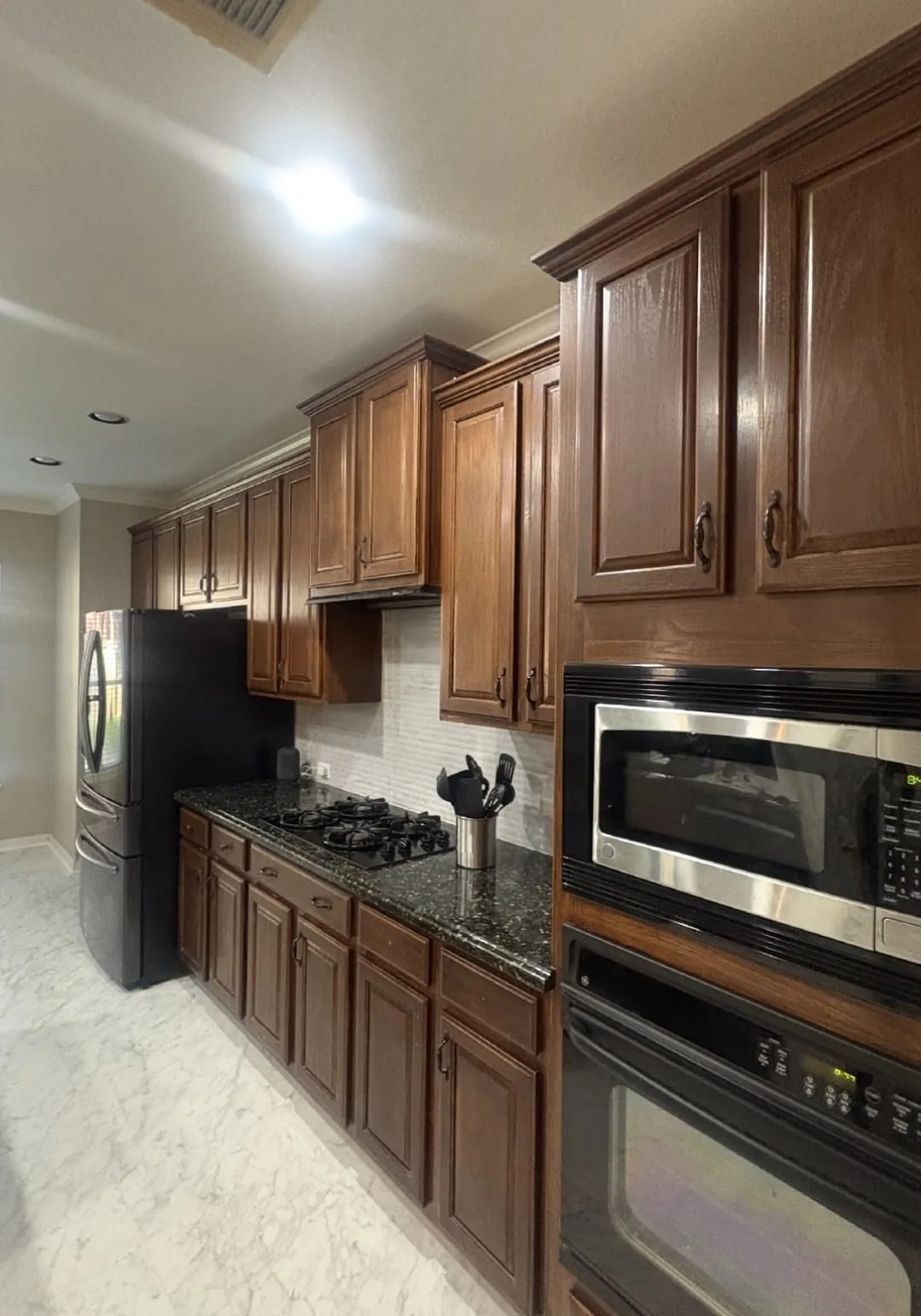 Dark, dated wood kitchen cabinets before cabinet refinishing in a Cinco Ranch home in Katy, TX