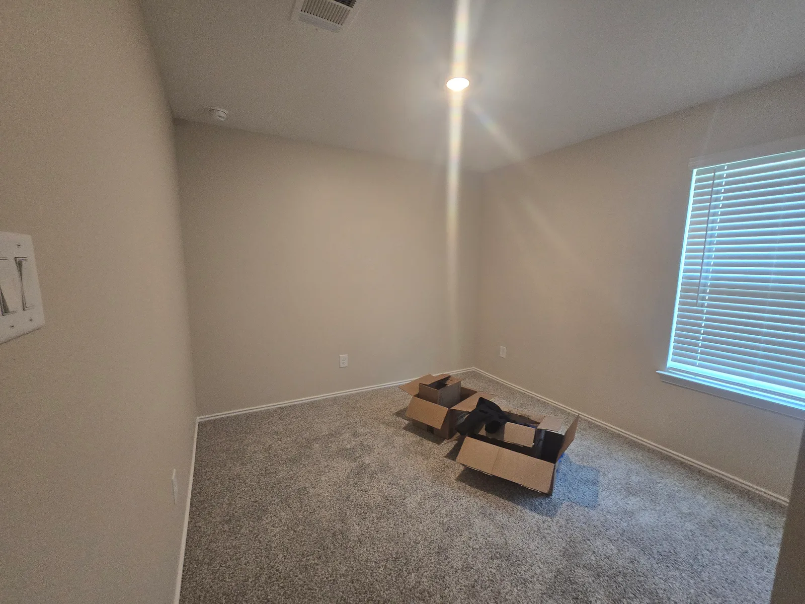 Empty bedroom with moving boxes in a Fulshear, TX home on move-in day, before interior painting
