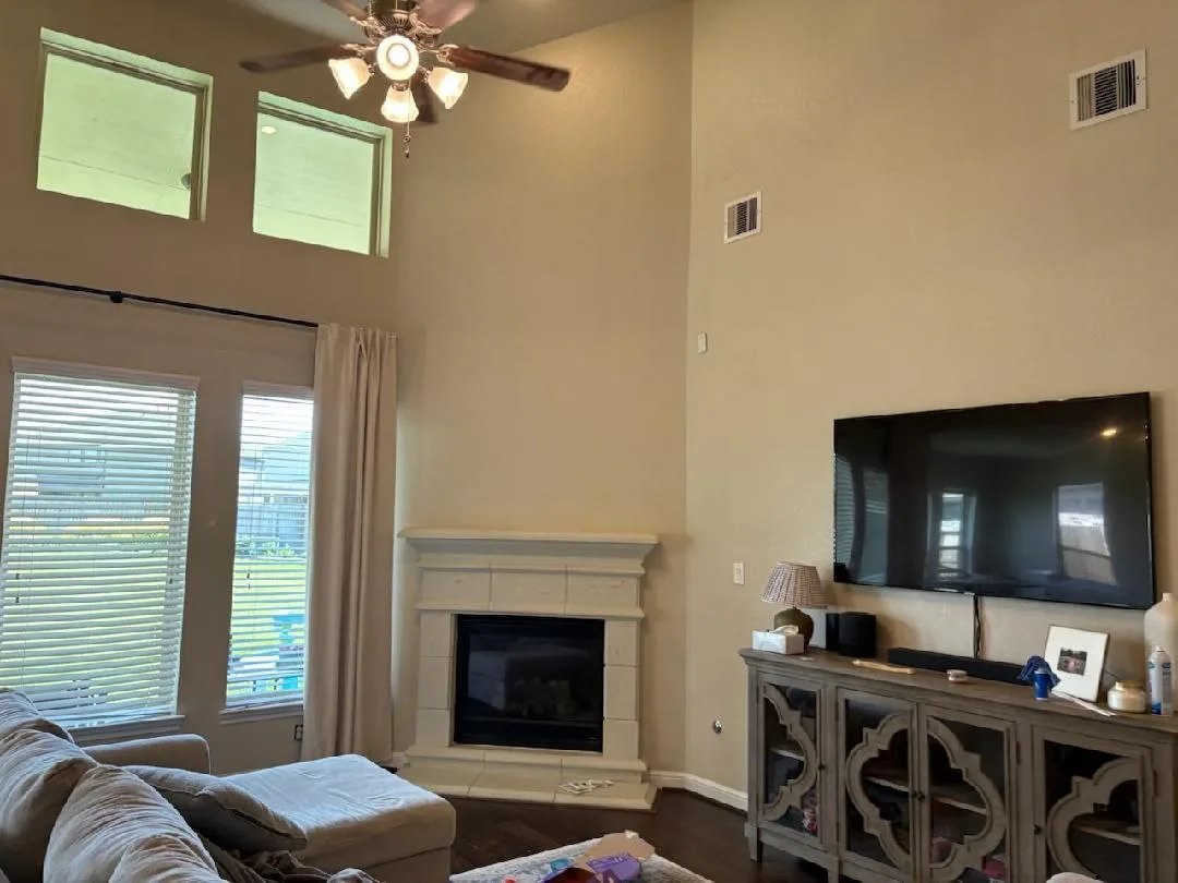 Great room with warm tan walls and fireplace freshly painted in a Fulshear, TX home by The Proud Paintbrush