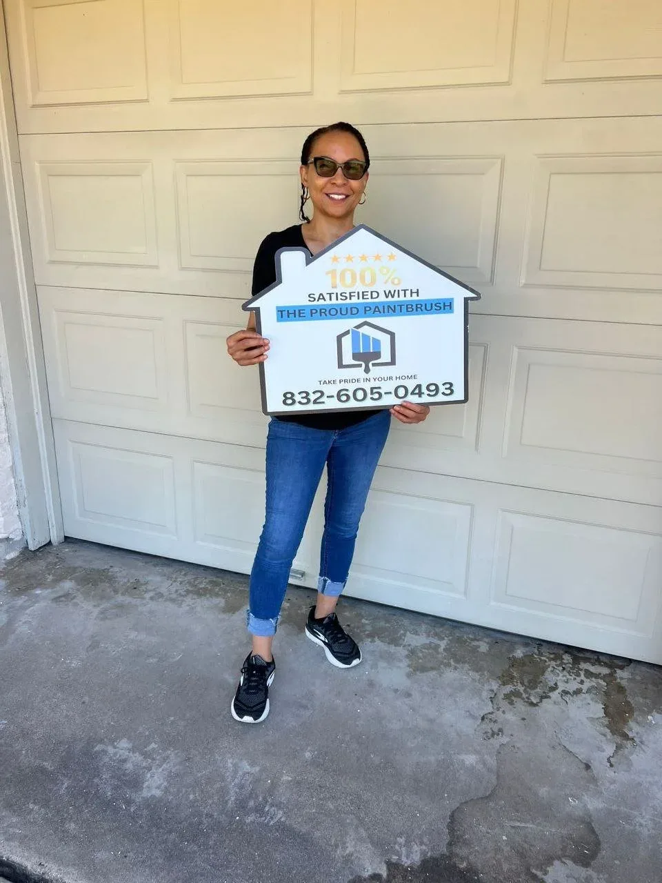 Happy homeowner holding satisfaction sign after painting project in Katy, TX by The Proud Paintbrush.