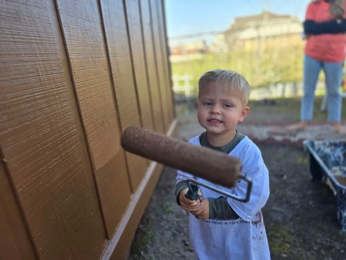 Isaac helping paint and learning at the family friendly Paint It Forward event in Sugar Land Texas
