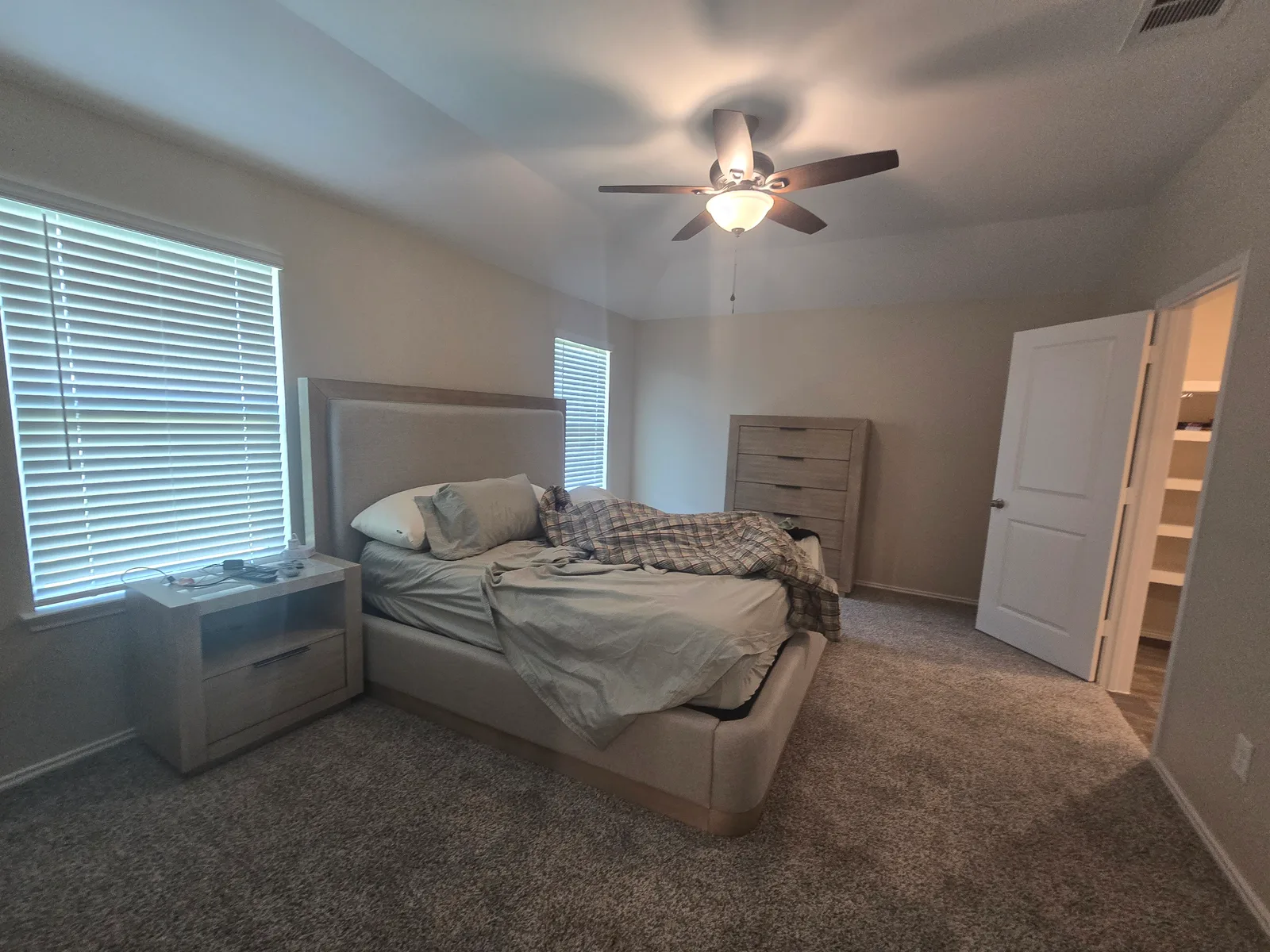 Primary bedroom with builder-grade white walls in a Fulshear, TX home on move-in day, before whole-home interior painting