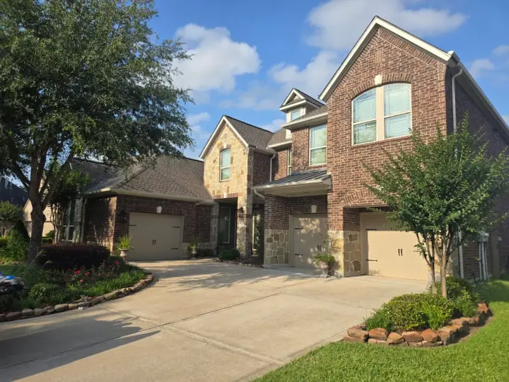 Exterior repaint of a brick home with stone accents, highlighting architectural details and blending natural materials with updated paint finishes.