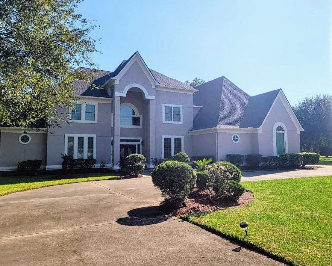 Large stucco house painted gray with white trim in West Houston, Texas