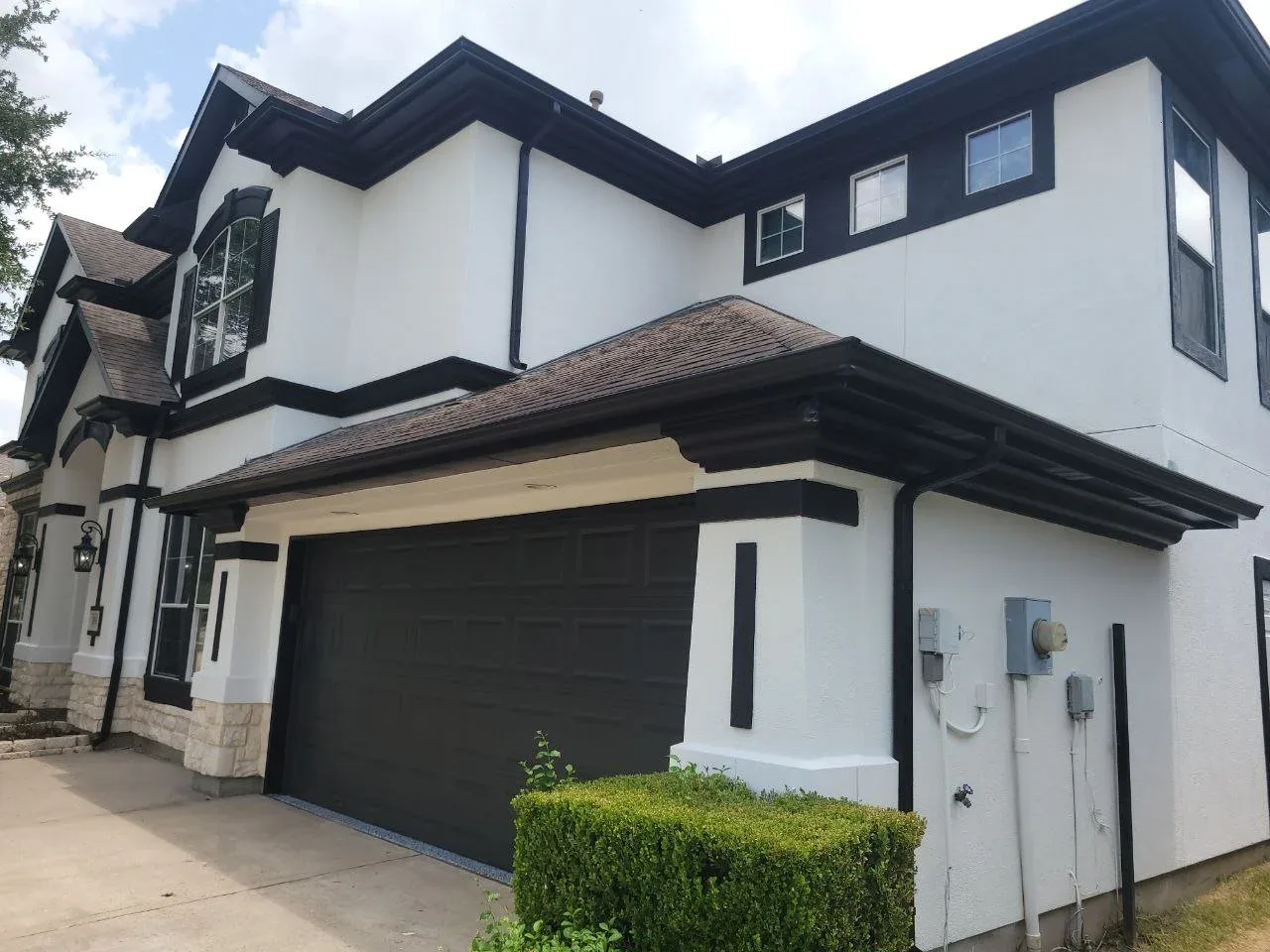 White and black stucco two-story home exterior in Missouri City, TX by The Proud Paintbrush